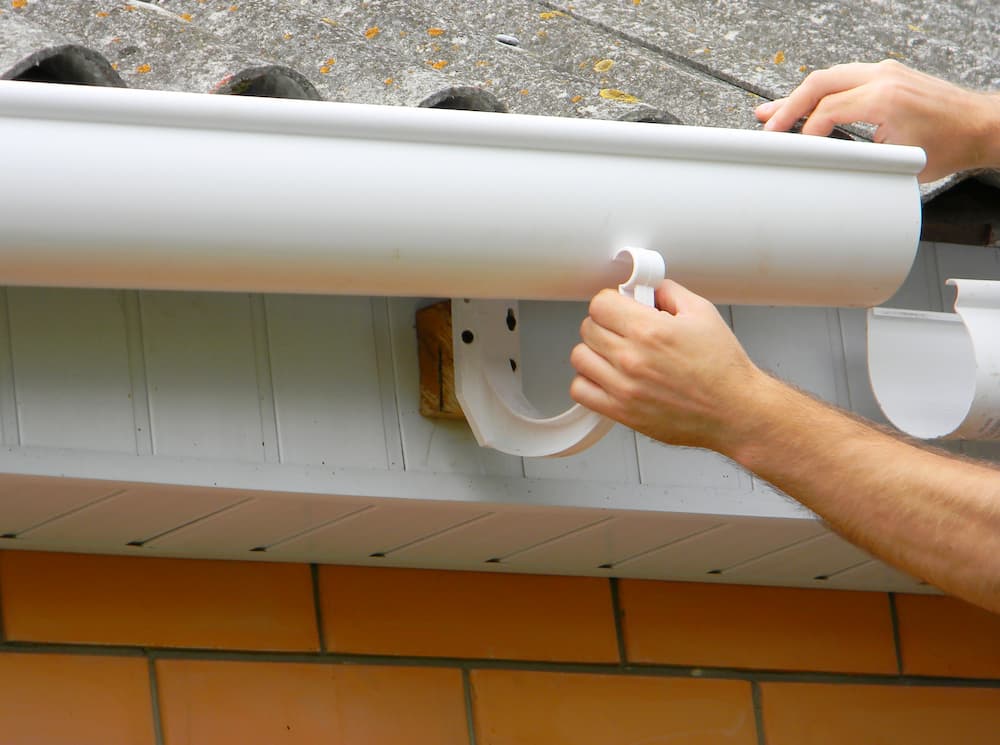 Installing a new gutter section along a home's roofline