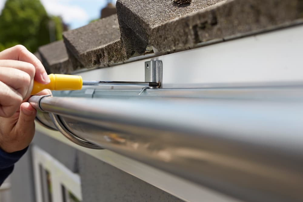 Tightening gutter fasteners with a screwdriver during repair